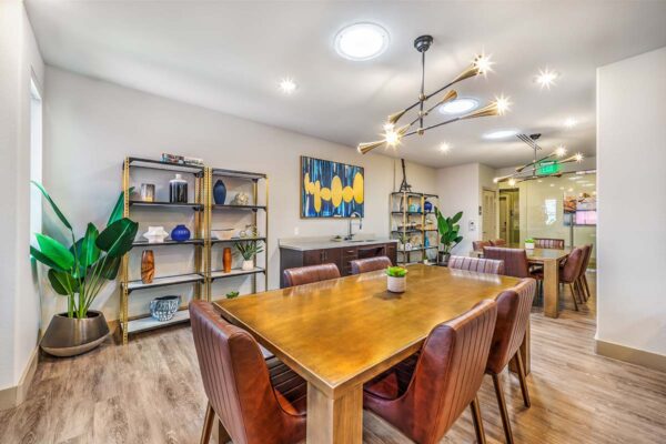 Lounge with large wood tables, shelves with decor, artwork, and sculptured chandeliers.