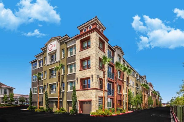 Aspire at Tesora apartments with lush landscaping, large palm trees, and garages.