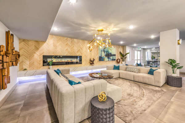 Lounge with plush seating, sculptural chandelier, and large fireplace.