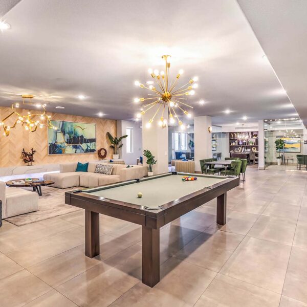 Lounge with plush seating, pool table, sculptural chandeliers, and fireplace.