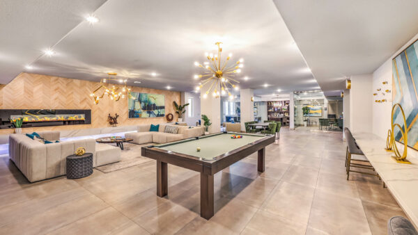 Lounge with plush seating, pool table, sculptural chandeliers, and fireplace.