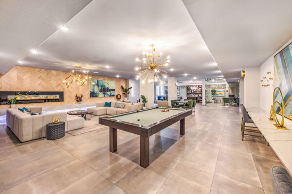 Lounge with plush seating, pool table, sculptural chandeliers, and fireplace.