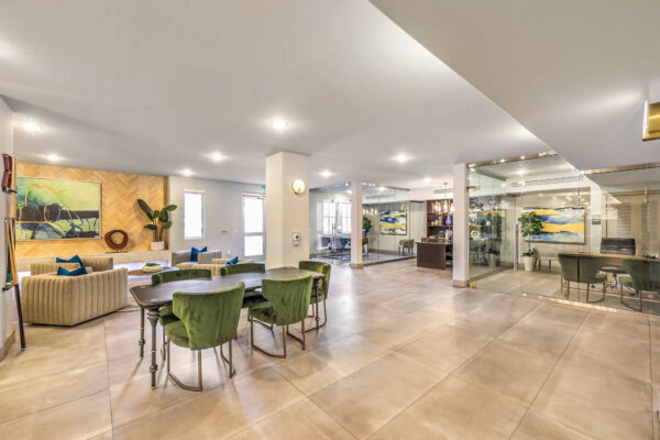 Clubroom with plush seating, office table with chairs, and glass wall offices.