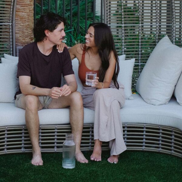 Friends sitting together with glasses of water on outdoor couch.