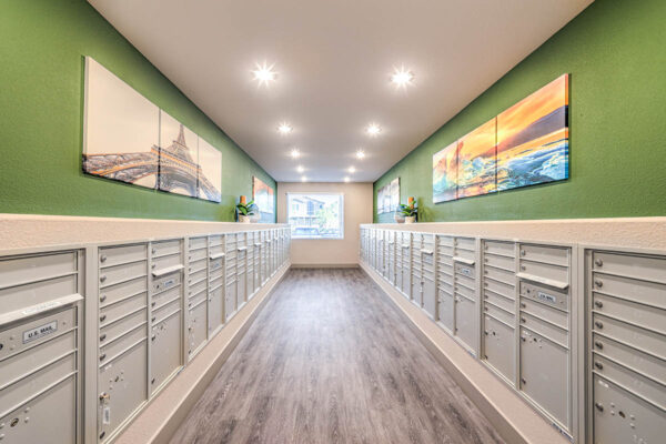 Mail room with mailboxes, potted plants, and large artwork.