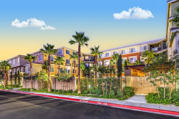 Capriccio apartments at dusk with glowing courtyard and tall palm trees.