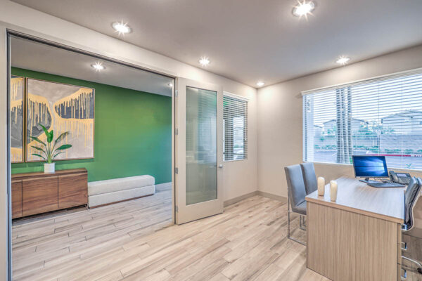 Leasing office with wood floor, desk with computer, and large window.