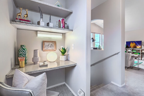 Built in computer desk with shelves and decor next to staircase.
