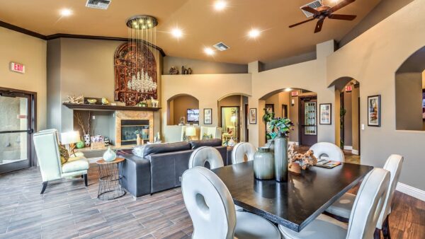 Clubhouse lounge with plush seating, elegant decor, dining table with chairs, and fireplace.