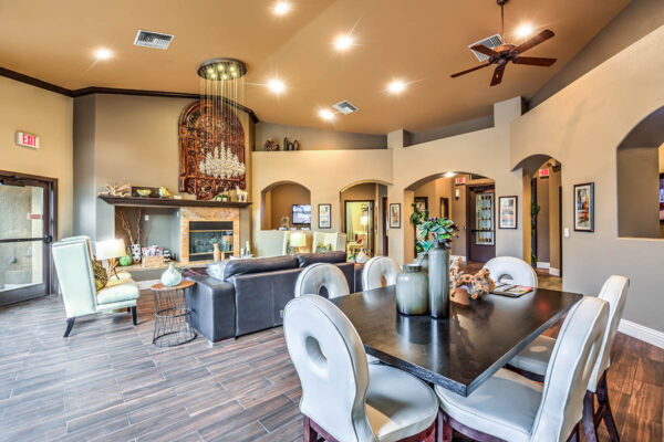 Clubhouse lounge with plush seating, elegant decor, dining table with chairs, and fireplace.