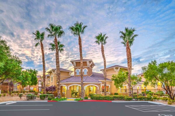 Chateau Calais office entrance with elegant architecture, lush landscaping, and tall palm trees.