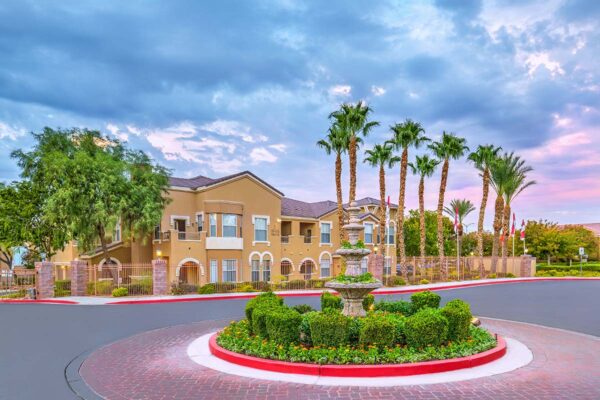 Chateau Calais entry with paved entrance, lush landscaping, and tall palms.