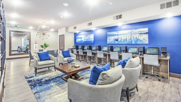 Business center with computer desks, brass light fixture, and plush chairs.