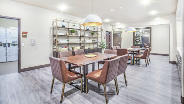 Lounge with wood tables, leather chairs, shelves with decor, and laundry room.