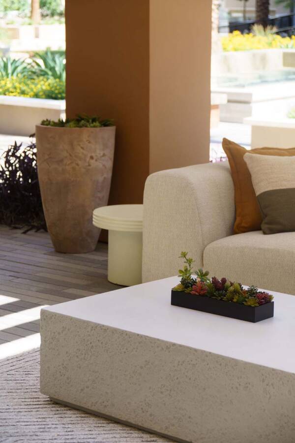 Outdoor lounge with stone coffee table, large planters, and plush couch.