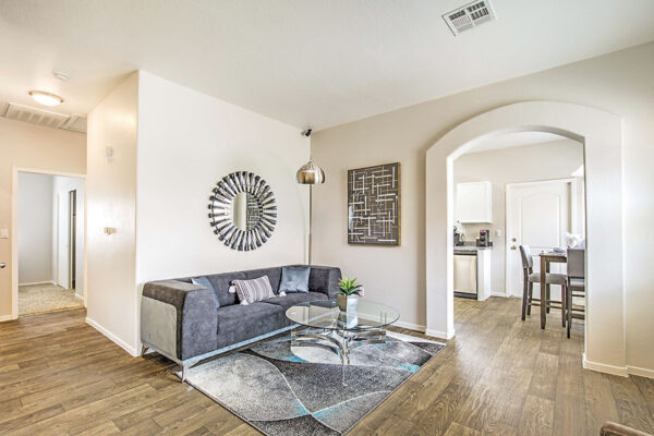 Living room with wood floor, plush couch, glass coffee table, standing lamp, and decor.