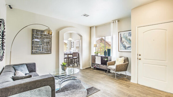 Living room with wood floor, plush seating, bar cart with decor, and large windows.