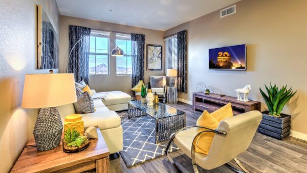 Living room with wood floor, plush leather seating, large artwork, and large window with curtains.