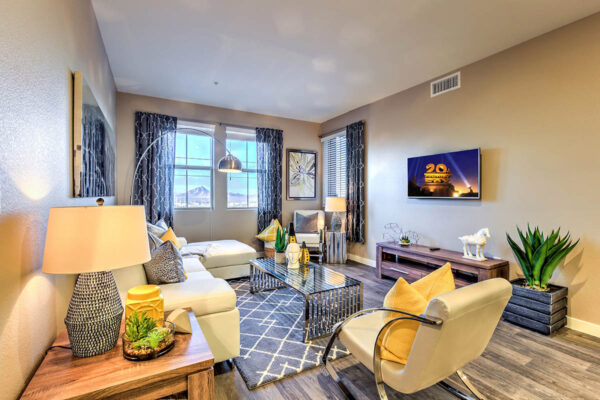 Living room with wood floor, plush leather seating, large artwork, and large window with curtains.