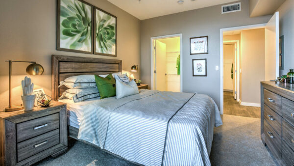 Bedroom with carpet, wood bed with headboard, bedside drawers with lamps, and door to closet.
