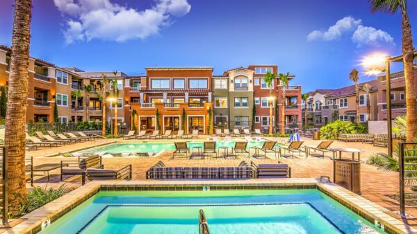 Pool area with spa, lounge chairs, couches, rooftop patio, and tall palms.