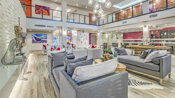 Clubroom with wood tile floor, plush couches, glass light fixture, art sculpture, and mezzanine.