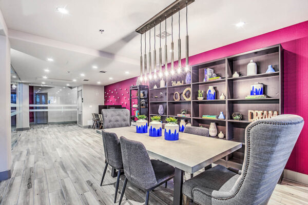 Business center at Inspire Apartments in Las Vegas, with large table, plush chairs, computer desks, and shelves with decor.