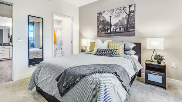 Bedroom with carpet, wood bed with headboard, bedside chests with lamps, and closet door.
