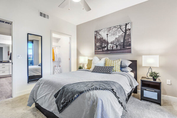 One-bedroom Las Vegas apartment with carpet, wood bed with headboard, bedside chests with lamps, and closet door.