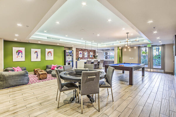 Game room with pool and poker tables, plush chairs, vending machine, and pop art posters at Inspire Apartments in Las Vegas