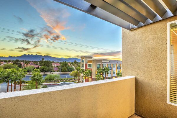 Balcony overlooking Inspire apartments in Northwest Las Vegas with lush landscaping and tall palm trees.