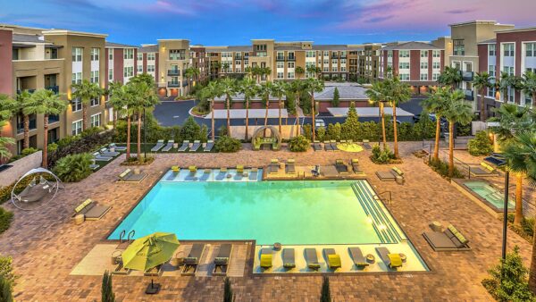 Overhead view of pool area with lounge chairs, daybeds, gazebos, and tall palm trees.