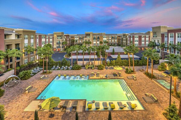 Overhead view of pool area at Inspire Apartments in Northwest Las Vegas with lounge chairs, daybeds, gazebos, and tall palm trees.