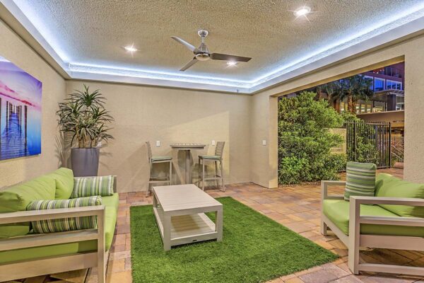 Indoor/outdoor lounge with plush seating, large potted plant, artwork, and ceiling fan at Inspire Apartments in Las Vegas