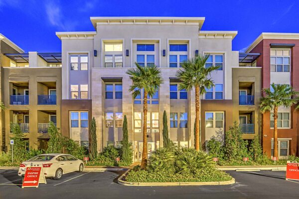 Inspire Apartments in Las Vegas with modern architecture, lush landscaping, tall palms, and ample parking.