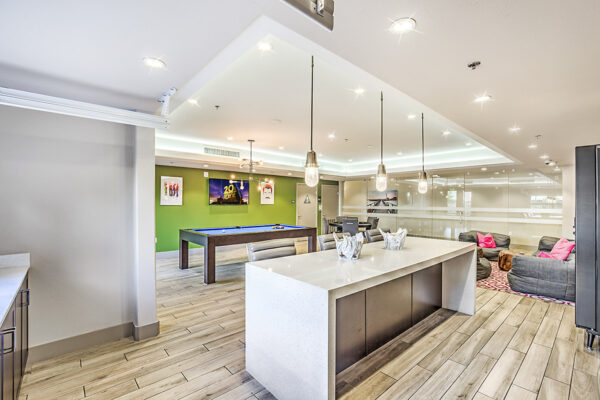 Game room with pool and poker tables, plush chairs, vending machine, and pop art posters at Inspire Apartments in Las Vegas