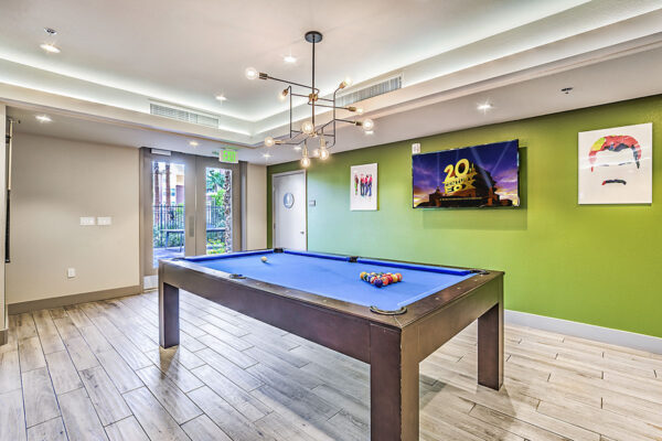 Game room with pool table, metal light fixture, pop art posters, and TV at Inspire Apartments in Las Vegas
