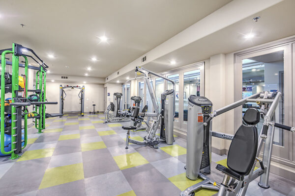 Fitness center with cardio machines, weight equipment, tile floor, and bright lights at Inspire Apartments in Northwest Las Vegas
