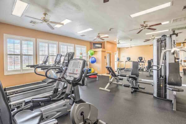Fitness center with cardio machines, weight equipment, and TV.