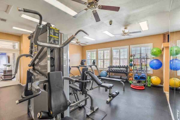 Fitness center with cardio machines, weight equipment, and TV.