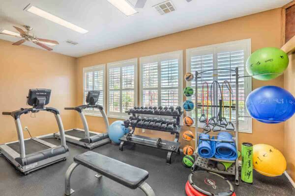Fitness center with cardio machines, weight equipment, and TV.