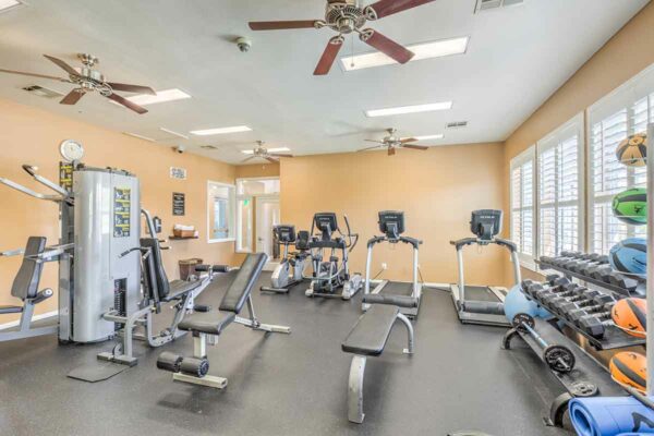 Fitness center with cardio machines, weight equipment, and TV.