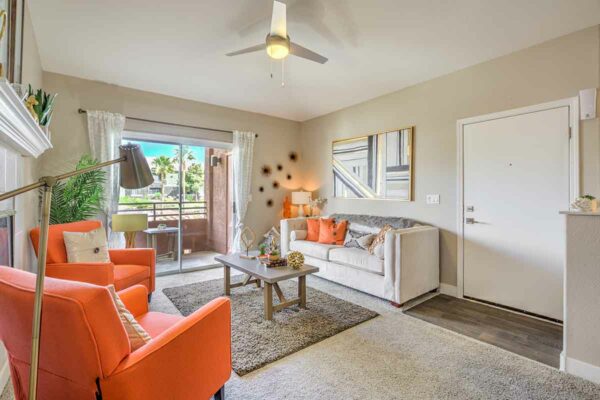 Living room with carpet, plush seating, wall art, ceiling fan, and sliding door to balcony.