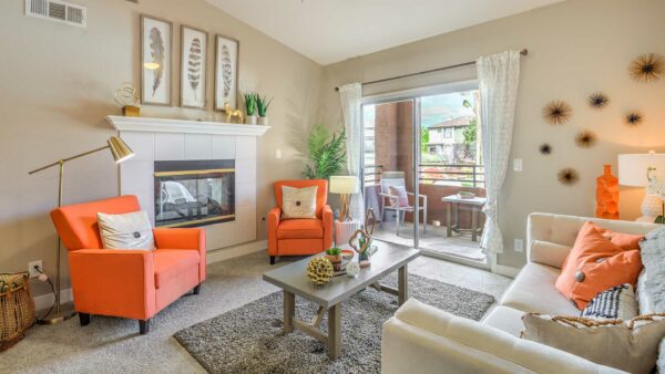 Living room with carpet, plush seating, wall art, fireplace, and sliding door to balcony.