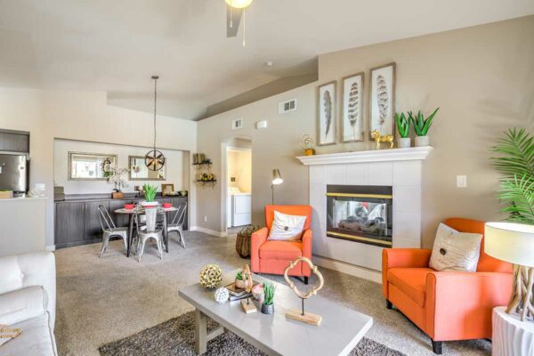 Living room with carpet, plush seating, wall art, fireplace, and dining set.