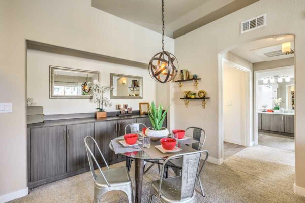 Dining area with metal light fixture, cabinets with decor, and dining table with metal chairs.