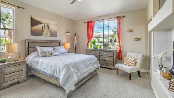 Bedroom with carpet, plush bed, wood furniture, large artwork, and fireplace.