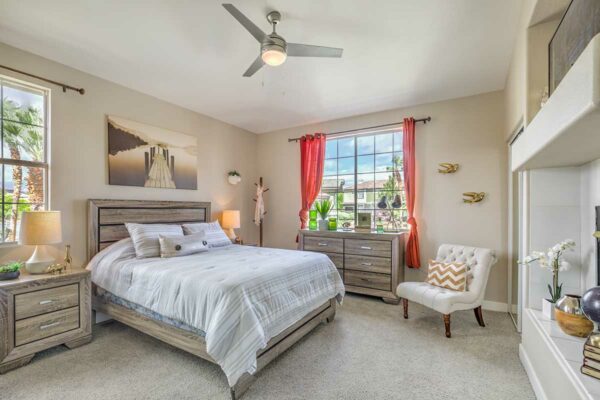 Bedroom with carpet, plush bed, wood furniture, large artwork, and fireplace.