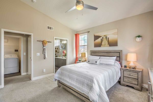 Bedroom with carpet, plush bed, bedside tables with lamps, and doors to hallway and bathroom.