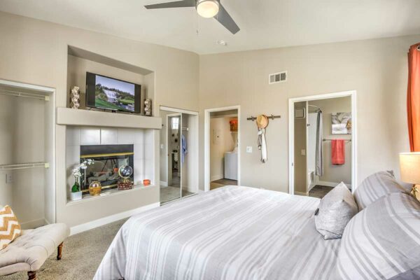 Bedroom with carpet, plush bed, fireplace, and doors to hallway and bathroom.